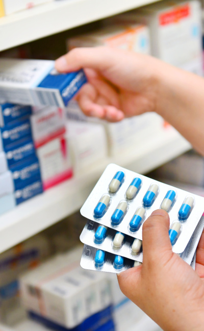 Hand legt Arzneimittel in ein Regal als Symbol für den Lehrgang Arzneimittelbeauftragter